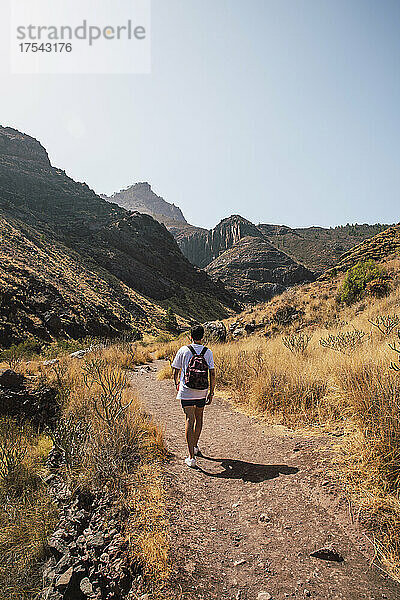 Junger Mann geht auf dem Weg in Richtung Bergkette  Gran Canaria  Kanarische Inseln  Spanien