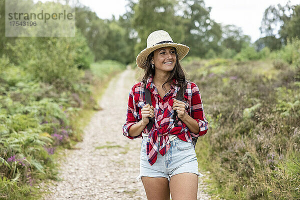 Lächelnde Frau mit Hut  die auf dem Fußweg bei Cannock Chase läuft