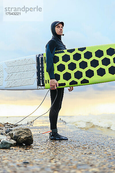 Confident surfer standing with surfboard on pier