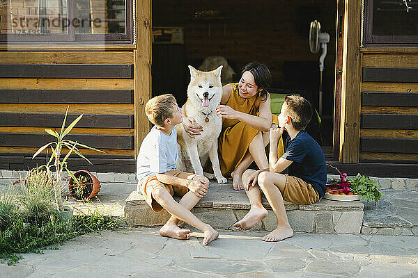Happy family sitting outside house with Akita dog