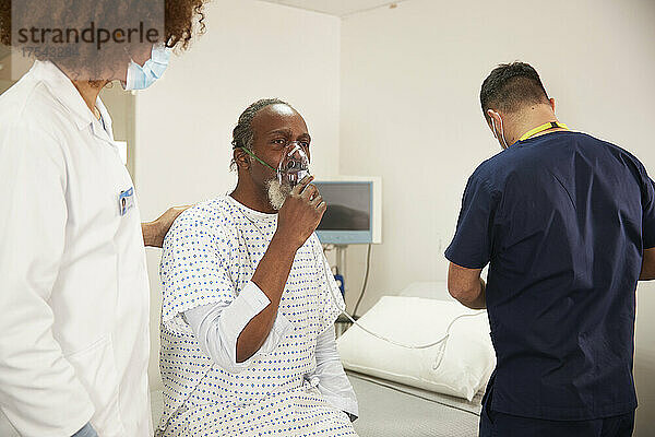 Ärztin spricht mit Patientin  die Sauerstoffmaske im Krankenzimmer trägt