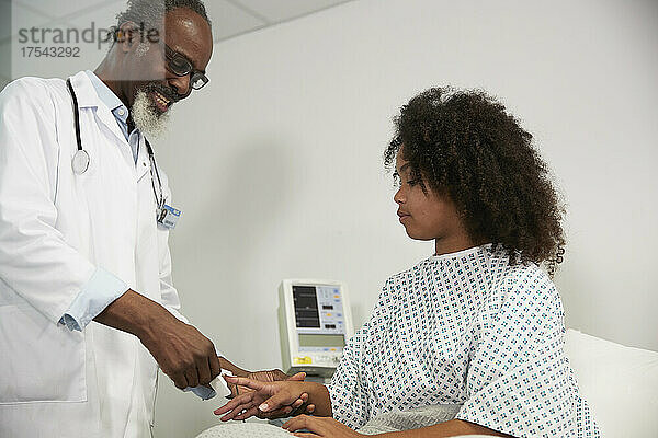 Arzt mit Pulsoximeter im Gespräch mit Patient im Krankenhaus