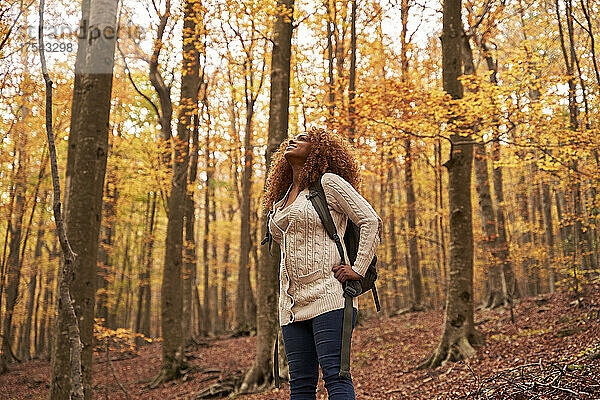 Frau mit Rucksack steht im Herbstwald