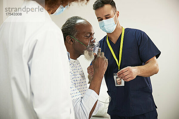 Patient passt Sauerstoffmaske mit Gesundheitsexperten im medizinischen Raum an