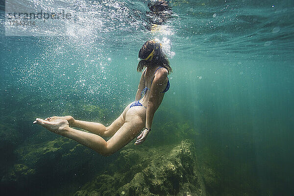 Young woman in bikini swimming in sea
