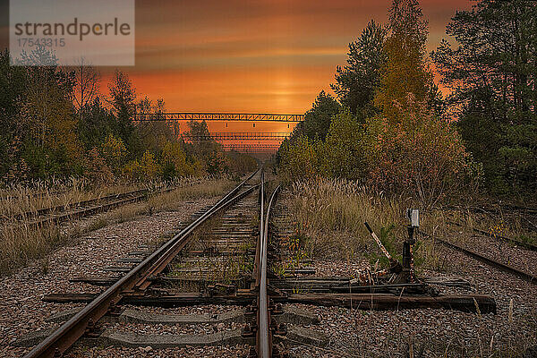 Ukraine  Kyiv Oblast  Chernobyl  Abandoned railroad tracks at fiery dusk