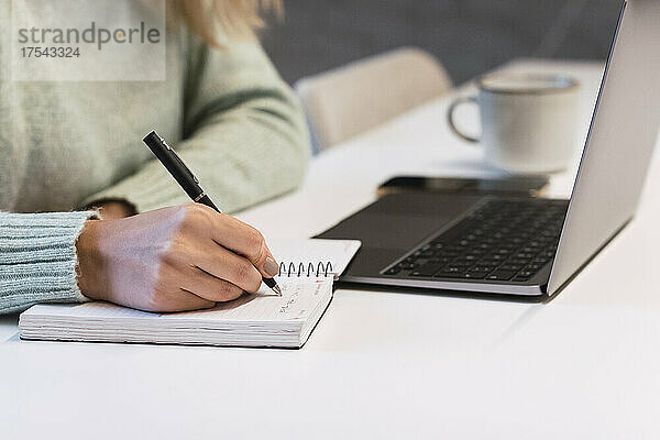 Geschäftsfrau schreibt Tagebuch am Schreibtisch im Studio