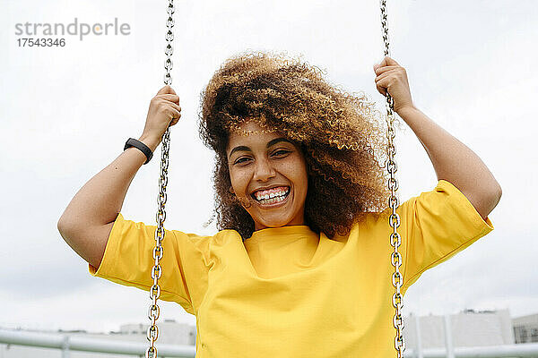 Smiling woman on swing in front of clear sky