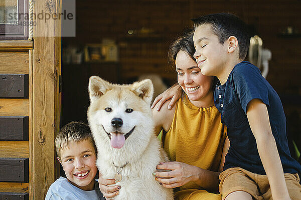 Smiling sons with mother and Akita dog outside house