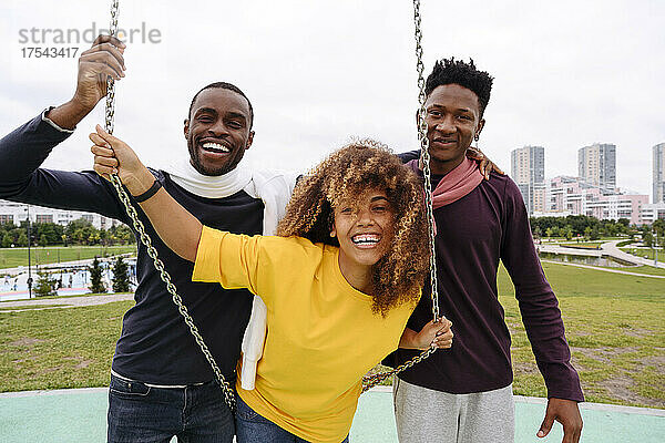 Cheerful friends by swing in park