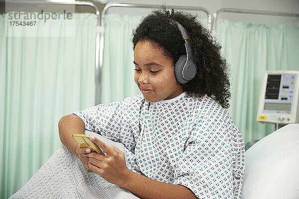 Patient with curly hair using smart phone at hospital