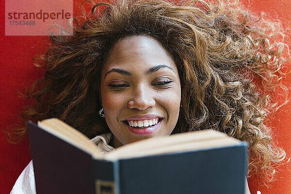 Smiling woman reading book on sofa