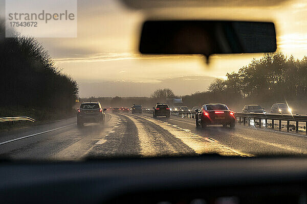 Verkehr auf der Autobahn bei Sonnenuntergang vom Auto aus gesehen
