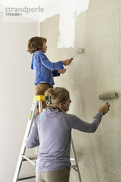 Eine Frau und ein achtjähriger Junge dekorieren einen Raum und streichen Wände.