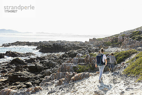 Teenagermädchen und jüngerer Bruder wandern auf einem Küstenweg am Meer