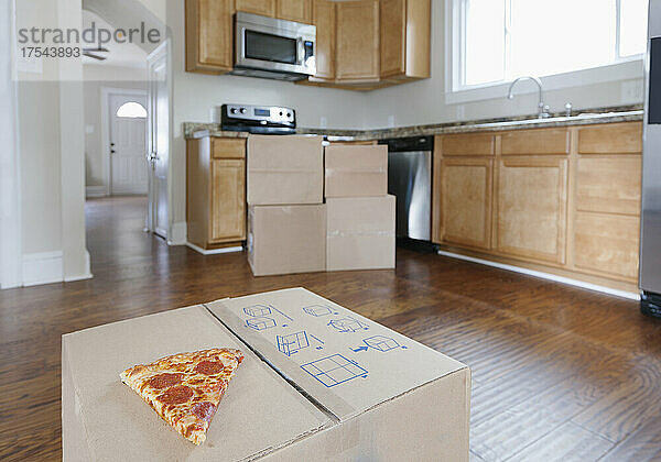 Umzug  Umzug  aufgestapelte Kartons in der Einbauküche des Hauses  ein Stück Pizza.