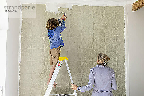 Eine Frau und ein achtjähriger Junge dekorieren einen Raum und streichen Wände.