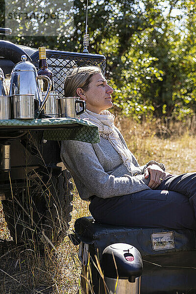 Erwachsene Frau sitzt in der Nähe von Safarifahrzeugen  Okavango Delta  Botswana