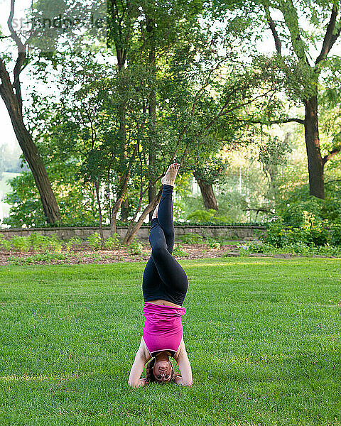 Frau balanciert in Yoga-Pose im Park.