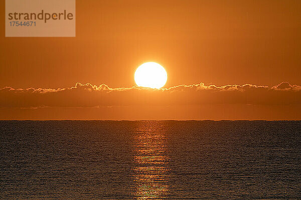Strahlender Sonnenaufgang am orangefarbenen Himmel über dem Meer