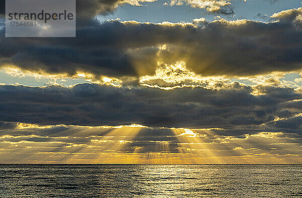 Sonnenstrahlen und goldene Wolken über dem Meer bei Sonnenaufgang