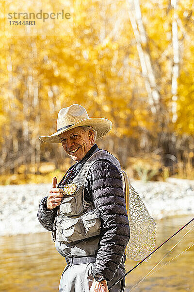 USA  Idaho  Bellevue  Porträt eines lächelnden älteren Mannes beim Fliegenfischen im Big Wood River im Herbst