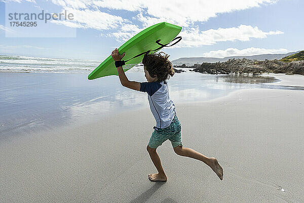 Südafrika  Hermanus  Junge (8-9) mit Surfbrett am Strand