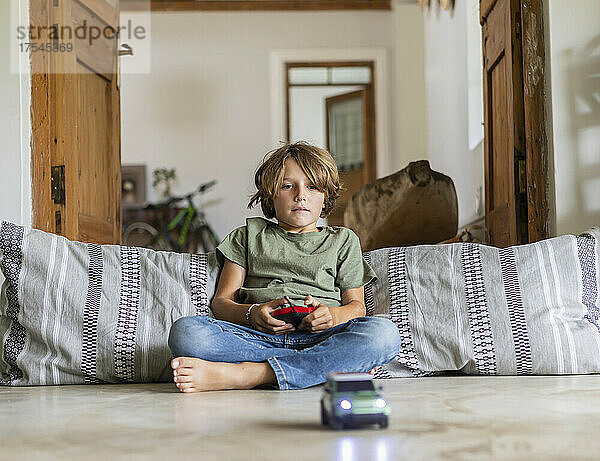 Junge (8-9) spielt zu Hause mit ferngesteuertem Spielzeugauto