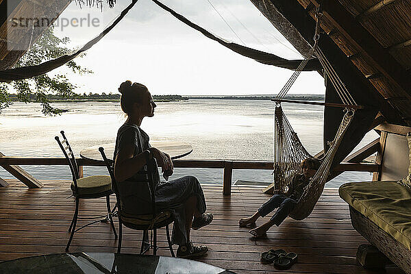 Afrika  Sambia  Livingstone  Bruder (8–9) und Schwester (16–17) entspannen sich in einer Lodge am Sambesi