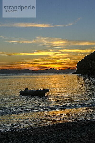 Blick auf Schlauchboot in kleiner Bucht von Elba bei Sonnenuntergang  am Horizont Silhouette von Bergkette von französische Insel Korsika  Morcone  Elba  Toskana  Italien  Europa