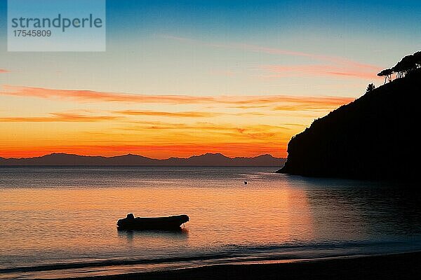 Blick auf Schlauchboot in kleiner Bucht von Elba unmittelbar nach Sonnenuntergang  am Horizont Silhouette von Bergkette von französische Insel Korsika  Morcone  Elba  Toskana  Italien  Europa