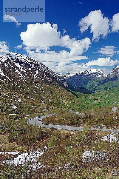 Straße führt durch frühlingshafte Landschaft an teils verschneiten Bergen vorbei talwärts  Almwiesen  Langvatn  Geiranger  Norwegen  Europa