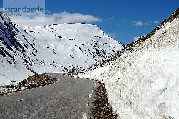 Straße führt entlang hoher Schneewände und verschneiter Berge aufwärts  Langvatn  Geiranger  Norwegen  Europa