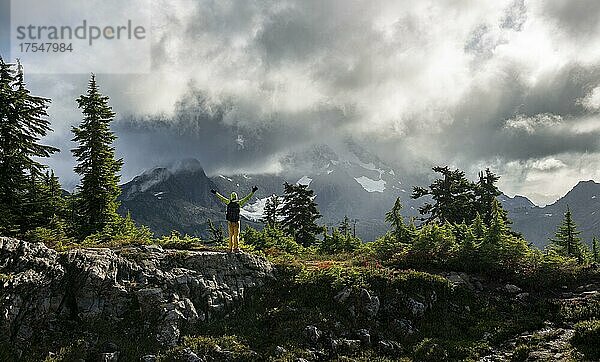 Wanderer streckt die Arme in die Luft  vor wolkenverhangenem Mt. Shuksan mit Schnee und Gletscher  dramatischer Wolkenhimmel  Mt. Baker-Snoqualmie National Forest  Washington  USA  Nordamerika