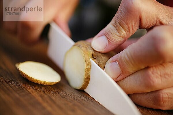 Badische Küche  Topinambur (Helianthus tuberosus)  Erdapfel  Erdbirne  Knollen schneiden  Männerhände  Messer  Holzbrett  Deutschland  Europa