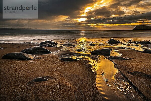 Sandstrand mit Steinen an Nordatlantik mit Felsnadel und Wolkenhimmel bei Sonnenuntergang  Halbinsel Dingle  Kerry  Irland  Europa