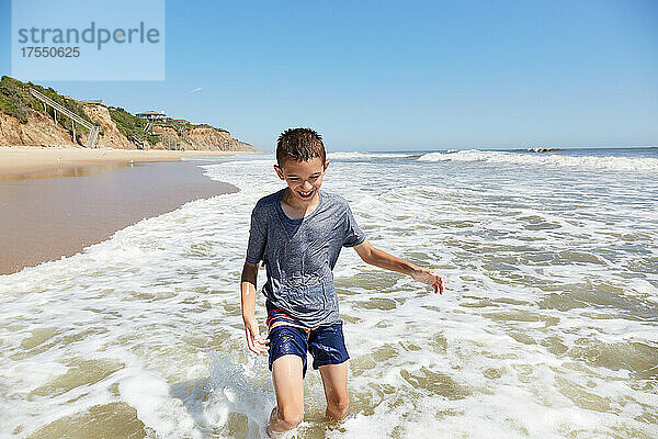 USA  New York  Montauk  lächelnder Junge (8-9)  der in den Meereswellen spielt