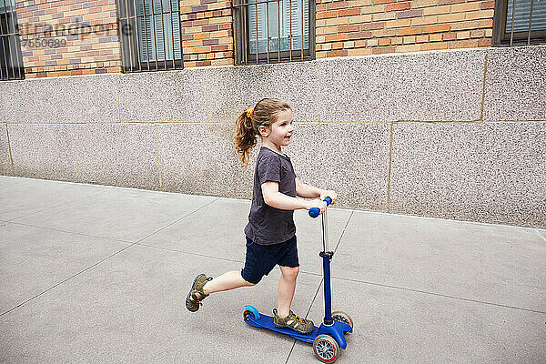USA  New York  New York City  Mädchen (2-3) fährt Tretroller auf Bürgersteig