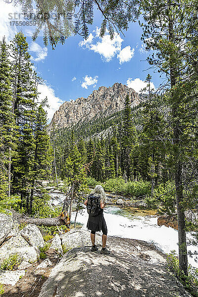 USA  Idaho  Stanley  ältere Wanderin blickt auf den rauschenden Bach in den Sawtooth Mountains