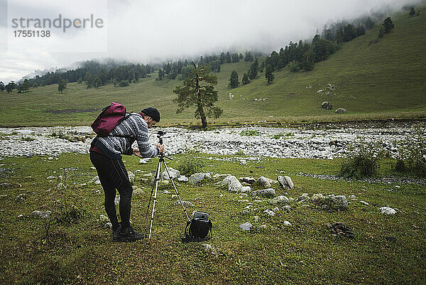 Russland  Karatschai-Tscherkessien  Arkhyz  Kaukasus  Wanderer fotografiert mit Stativ in nebligen Bergen