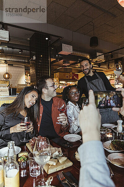 Ausgeschnittenes Bild eines Mannes  der mit seinem Smartphone im Restaurant ein Foto von einem Mann und einer Frau macht