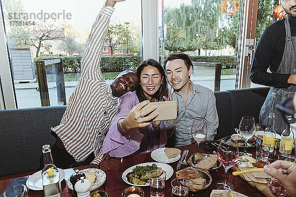 Frau macht Selfie mit männlichen Freunden beim Feiern in einer Bar nach der Arbeit