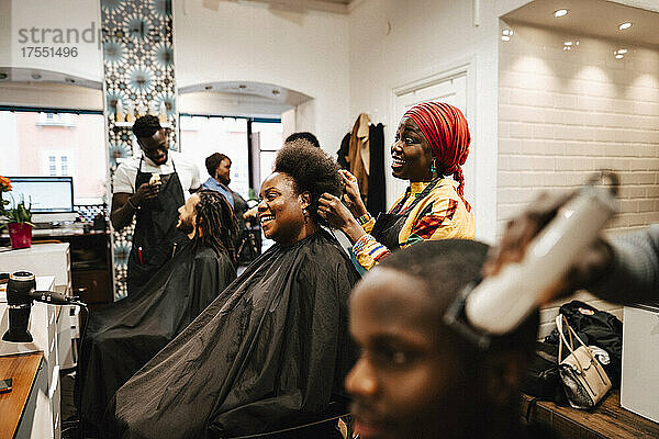 Multirassischer Haarspezialist beim Friseur  der männliche und weibliche Kunden frisiert