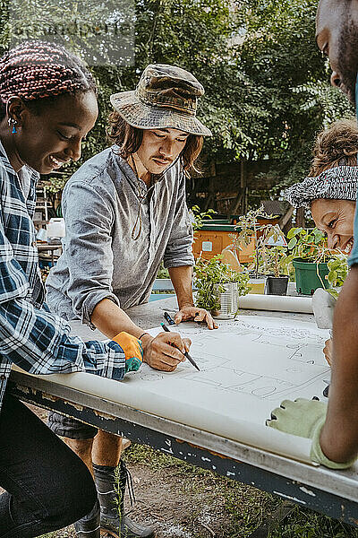 Männliche und weibliche Umweltschützer zeichnen auf Papier in einem städtischen Bauernhof
