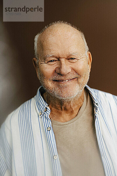 Porträt eines lächelnden älteren Mannes vor braunem Hintergrund