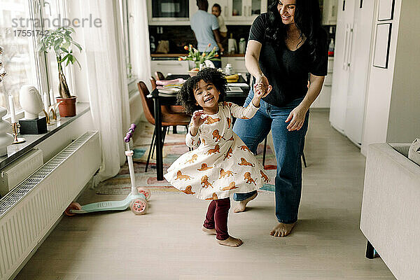 Glückliche Mutter und Tochter tanzen in der Küche zu Hause