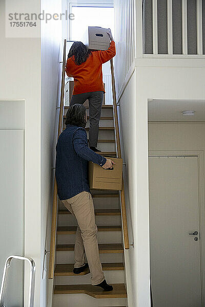 Heterosexuelles Paar mit Umzugskartons auf der Treppe zu Hause