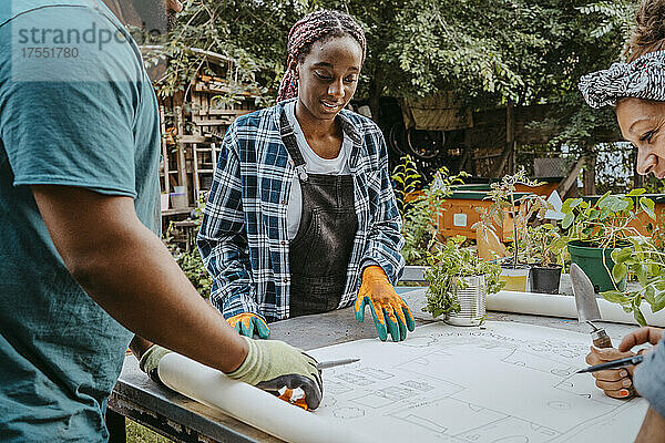 Weibliche und männliche Freiwillige bei der Prüfung eines Bauplans im Gemeinschaftsgarten