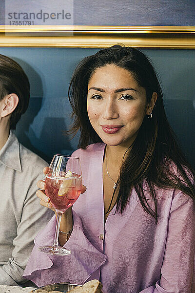 Porträt einer lächelnden Frau mit Wein  die neben einem männlichen Freund in einer Bar sitzt