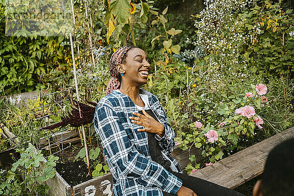 Fröhliche junge Frau  die lachend in einem städtischen Bauernhof sitzt